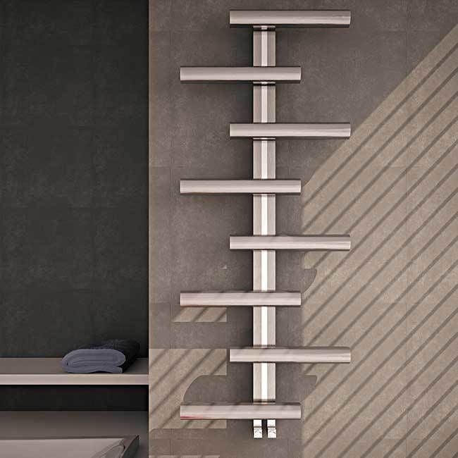 Towel radiator against a gray wall with a towel on a shelf below